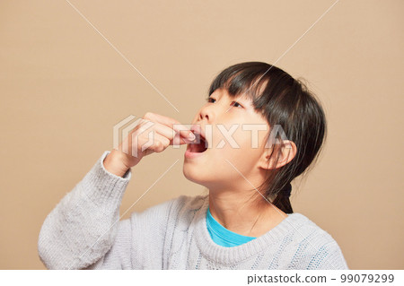 Elementary school girl taking medicine indoors 99079299