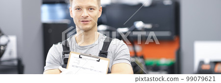 Male car mechanic holding clipboard in auto workshop Male car mechanic holding clipboard in auto workshop 99079621