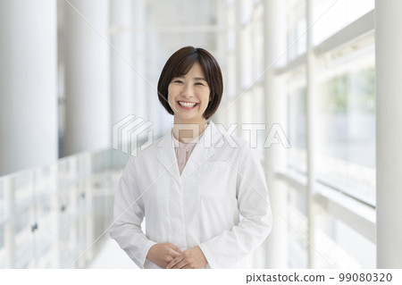 A young woman in a white coat looking at the camera portrait A young woman in a white coat looking at the camera portrait 99080320
