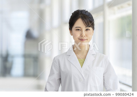 一位穿著白大衣的微笑的年輕女子看著相機肖像 99080424