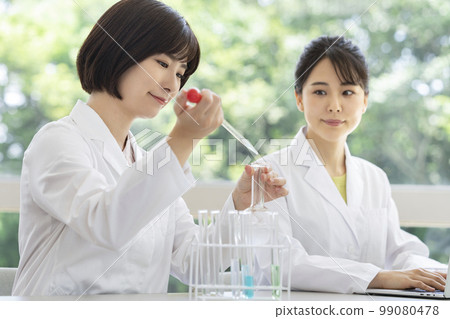 Two women in white coats doing experiments 99080478