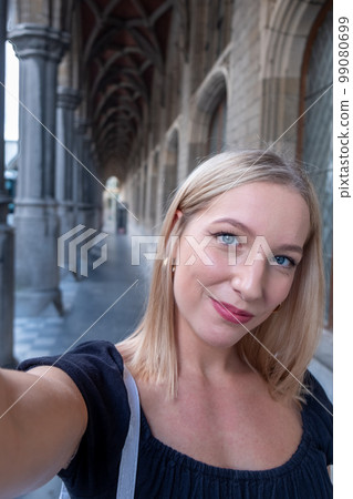 Beautiful young blonde woman wearing a black blouse and smiling confident making a selfie using a Beautiful young blonde woman wearing a black blouse and smiling confident making a selfie using a 99080699