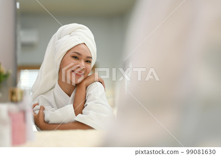 Gorgeous woman with towel on head hugging herself and looking in mirror. Self care and self esteem concept 99081630
