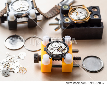 open mechanical watches in holders on wooden table 99082037
