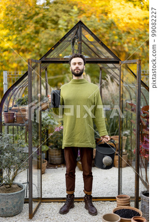 Stylish guy with watering can in garden 99082227