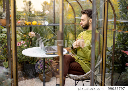 Man works remotely on laptop in garden 99082797