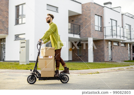Man drives electric scooter with cardboard packages 99082803