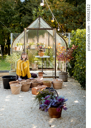 Woman planting flowers in jugs at garden Woman planting flowers in jugs at garden 99082812