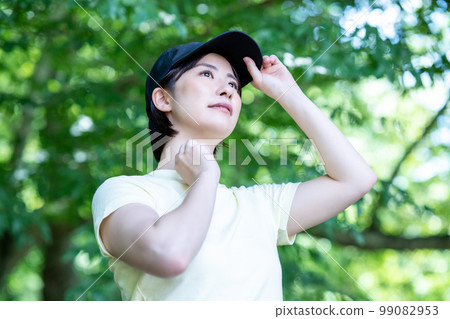 A woman wearing a hat refreshing in the fresh green A woman wearing a hat refreshing in the fresh green 99082953