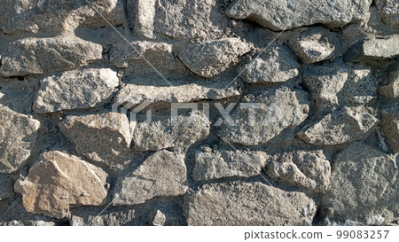 Stone wall texture background - grey stone siding with different sized stones. Part of a stone wall, for background or texture. Texture of a stone wall. 99083257