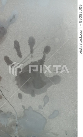 Hand trace on glass. Palm print on the frozen glass. Trace hands and fingers on the window covered with snow frost. 99083309