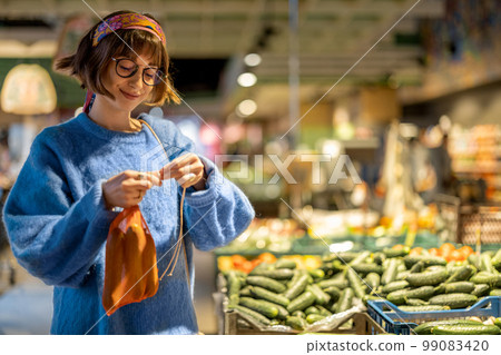 Woman chooses vegetables in supermarket Woman chooses vegetables in supermarket 99083420