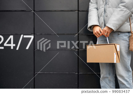 Holding a parcel on background of automatic post office machine 99083437