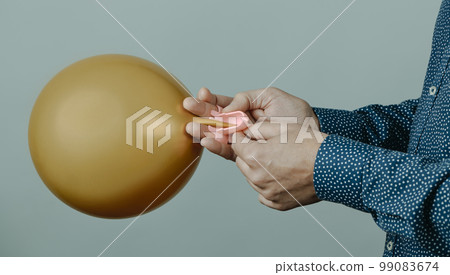 man ties an inflated golden balloon, banner format 99083674