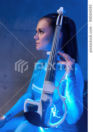 Side view of young woman violinist with electric fiddle Side view of young woman violinist with electric fiddle 99084095