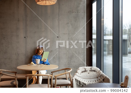 Woman works on touchpad at coffee shop Woman works on touchpad at coffee shop 99084142