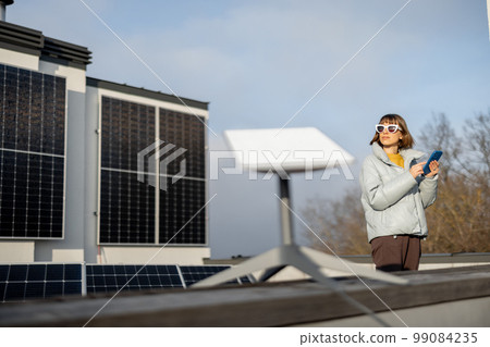 Woman uses satellite internet connection on roof of a house Woman uses satellite internet connection on roof of a house 99084235