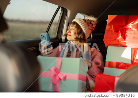Woman in car with Christmas presents Woman in car with Christmas presents 99084316