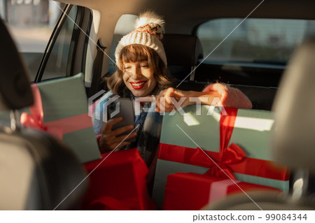 Woman in car with Christmas presents Woman in car with Christmas presents 99084344