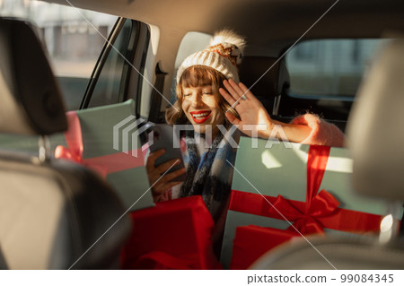 Woman in car with Christmas presents Woman in car with Christmas presents 99084345