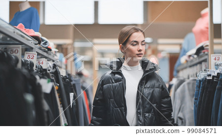 A young girl choosing and looking at clothes in the store. 99084571