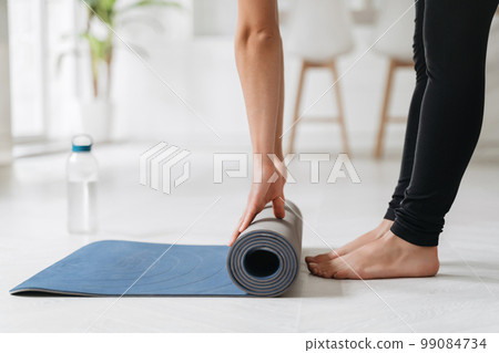 Fit girl preparing exercise mat for yoga session at home 99084734