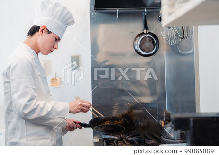 Male chef cooking in a frying pan Male chef cooking in a frying pan 99085089