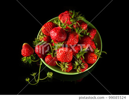 A lot of red ripe strawberries in a plate on a black background. Summer diet and vitamin set idea A lot of red ripe strawberries in a plate on a black background. Summer diet and vitamin set idea 99085524