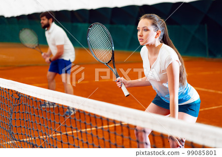 Pair of tennis players, man and woman waiting for service at indoor court 99085801