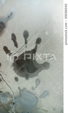 Hand trace on glass. Palm print on the frozen glass. Trace hands and fingers on the window covered with snow frost. 99086040