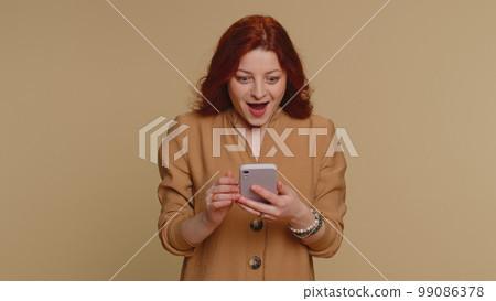 Happy excited woman use mobile phone say wow yes found out great big win news doing winner gesture Happy excited woman use mobile phone say wow yes found out great big win news doing winner gesture 99086378