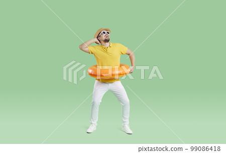 Funny cheerful man wearing life buoy waist having fun and fooling around on light green background. 99086418