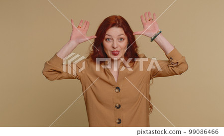 Funny joyful woman making playful silly facial expressions, grimacing, fooling around showing tongue 99086466
