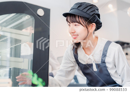 Young store clerk arranging products in showcase 99088533