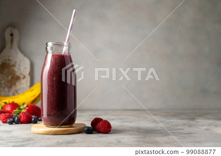 Bottle of berry smoothie in a glass. Strawberry, banana, blueberry healthy drink. Copy space. 99088877