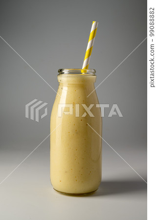 Bottle of mango, banana and yoghurt smoothie with a straw. 99088882