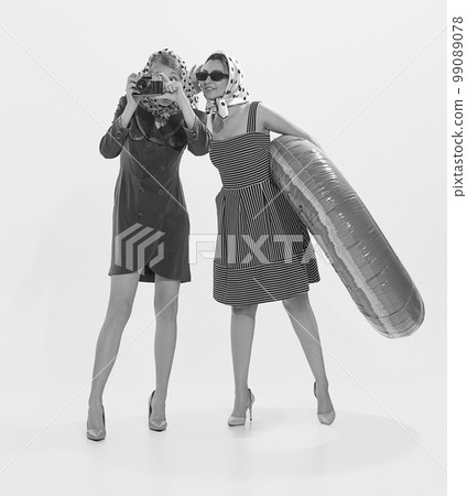 Portrait of two stylish young retro women travelling on cruise, taking photos, swimming. Black and white photography Portrait of two stylish young retro women travelling on cruise, taking photos, swimming. Black and white photography 99089078