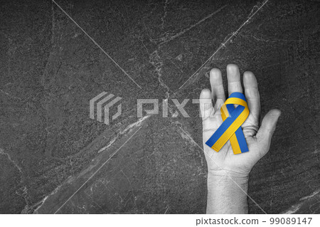blue yellow ribbon lies on the male palm 99089147
