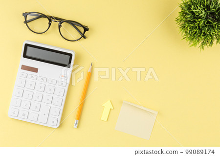 White calculator on a yellow background. 99089174