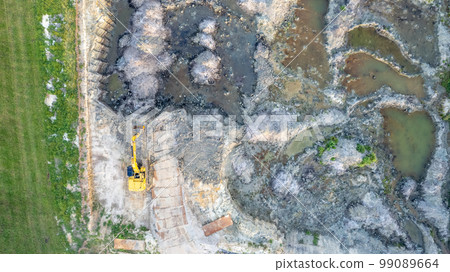 Yellow tracked bulldozer performs earthworks - aerial view shot. Yellow tracked tractor rakes the Yellow tracked bulldozer performs earthworks - aerial view shot. Yellow tracked tractor rakes the 99089664