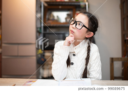 A girl wearing glasses who is worried while studying A girl wearing glasses who is worried while studying 99089675