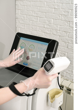 Cosmetologist's hand adjusting a modern laser epilation machine in a beauty salon. hair removing at beauty salon 99090923