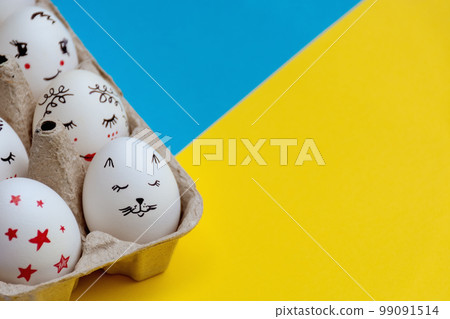 Soft Selective focus on White Easter eggs beautifully painted in Paper Tray on yellow blue background. Copy space. Conceptual idea - with Ukraine in heart Soft Selective focus on White Easter eggs beautifully painted in Paper Tray on yellow blue background. Copy space. Conceptual idea - with Ukraine in heart 99091514
