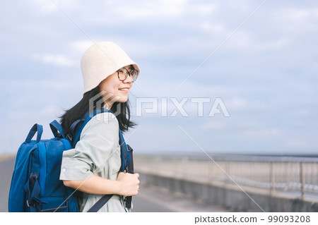 Young adult asian traveller woman side view with blue backpack standing at outdoor 99093208