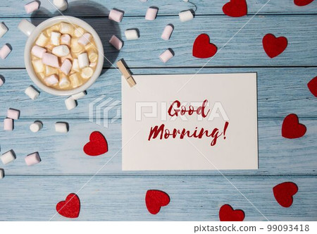 GOOD MORNING text on valentine card inscription positive quote phrase Greeting card with red envelope with white cup of coffee and marshmallows on wooden background. Romantic Small hearts Valentine 99093418
