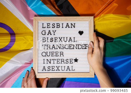 LGBTQIA description frame on Rainbow LGBTQIA flag made from silk material. LESBIAN, GAY, BISEXUAL, TRANSGENDER, QUEER, INTERSEX, ASEXUAL Symbol of LGBTQ pride month. Equal rights. Peace and freedom. LGBTQIA description frame on Rainbow LGBTQIA flag made from silk material. LESBIAN, GAY, BISEXUAL, TRANSGENDER, QUEER, INTERSEX, ASEXUAL Symbol of LGBTQ pride month. Equal rights. Peace and freedom. 99093485