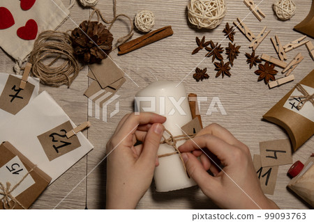 Unrecognizable young woman paint numbers on candles. Female making homemade advent calendar Made with your own hands step by step DIY crafts do it yourself. Preparation to christmas concept. Seasonal 99093763