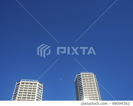 Apartment building and cloudless blue sky. The moon visible during the day. 99094362