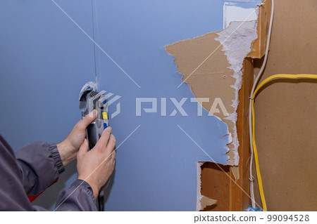 Renovation service work in house cutting off damaged plasterboard with using oscillating multi tool 99094528