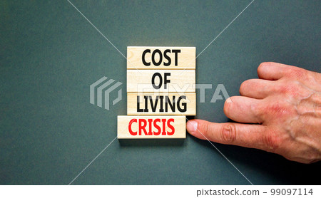 Cost of living crisis symbol. Concept words Cost of living crisis on wooden blocks. Beautiful grey table grey background. Businessman hand. Business cost of living crisis concept. Copy space. 99097114